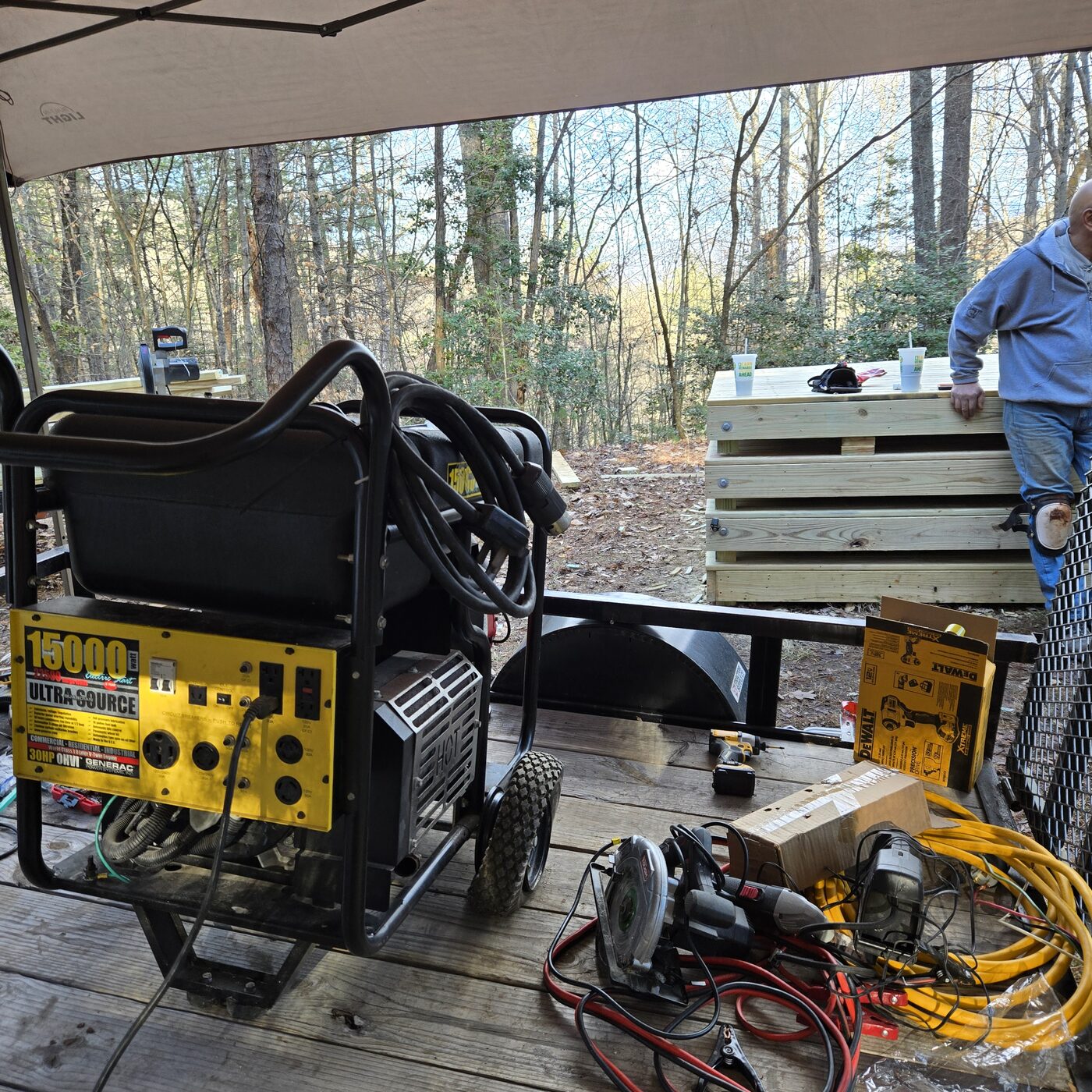 A portable generator, saws and extension cords under a canopy at the Cardinal Mountain Campground build site