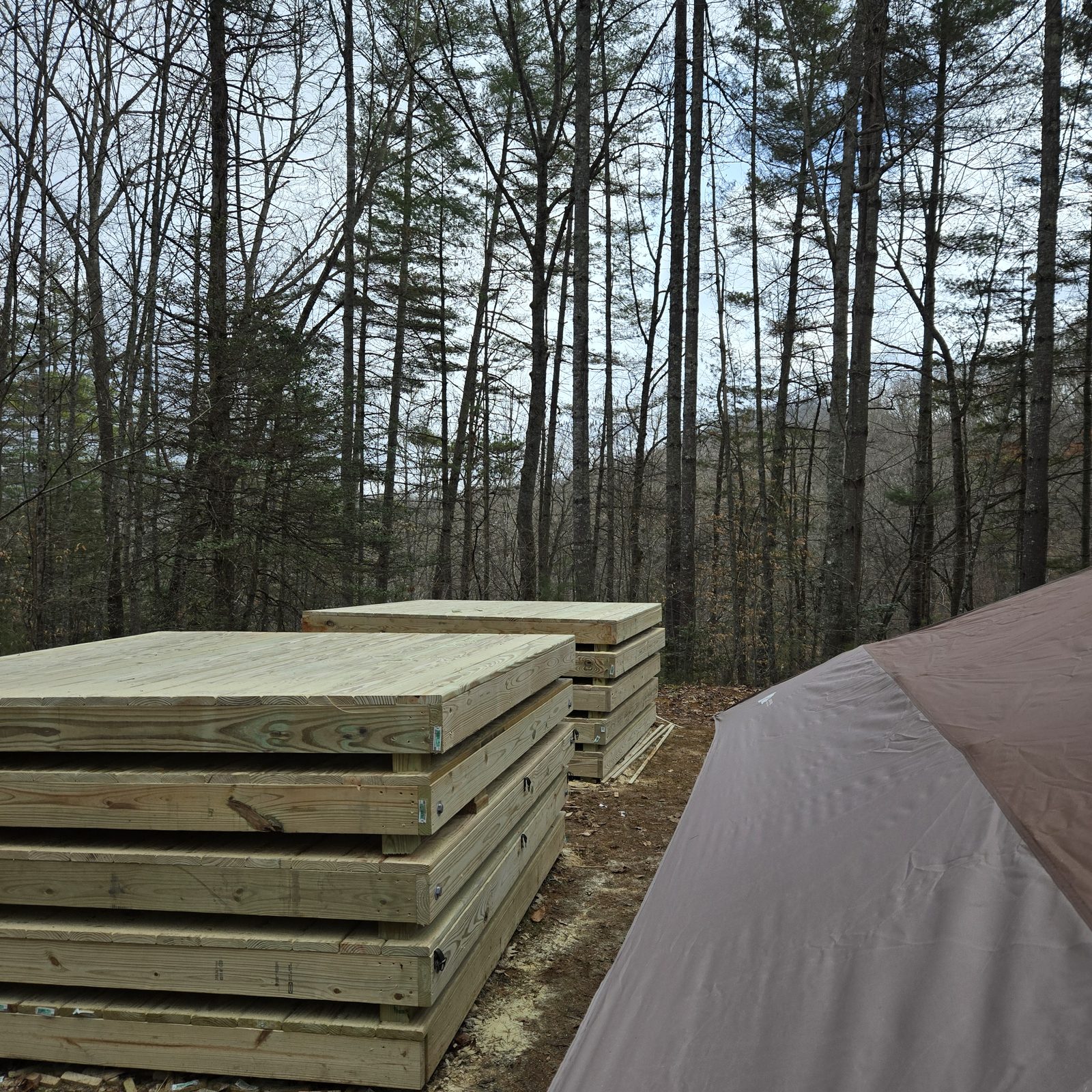 Stacked tent deck panels beside a tent at the Cardinal Mountain Campground work site