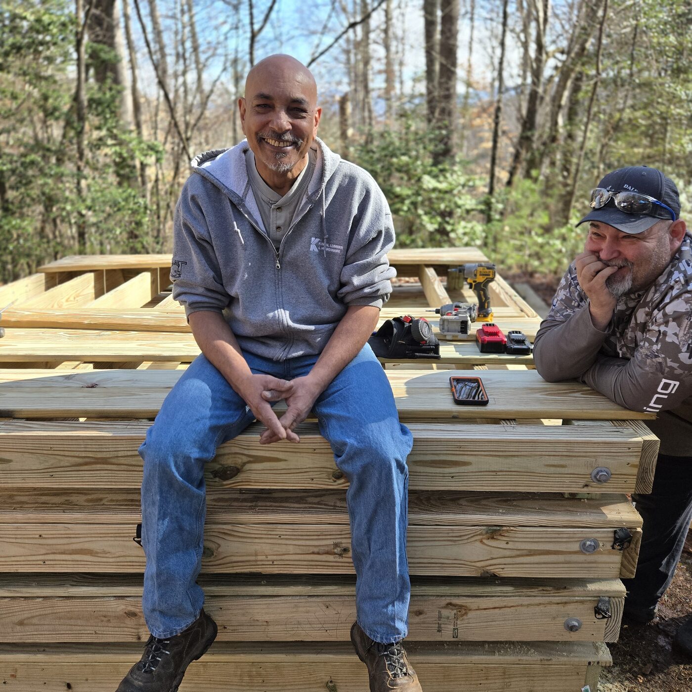 Two builders taking a break on a stack of finished tent deck panels at Cardinal Mountain Campground near Franklin, NC