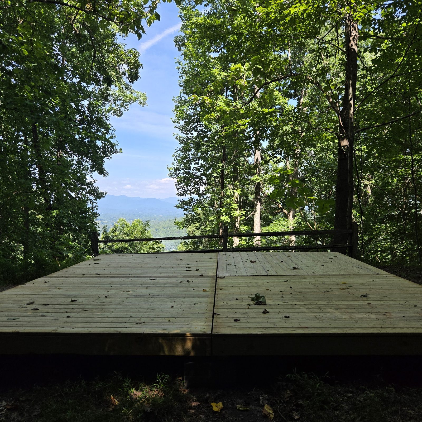 Campsite Smokies 17 at Cardinal Mountain Campground: a tent deck behind a split-rail fence with distant blue mountains