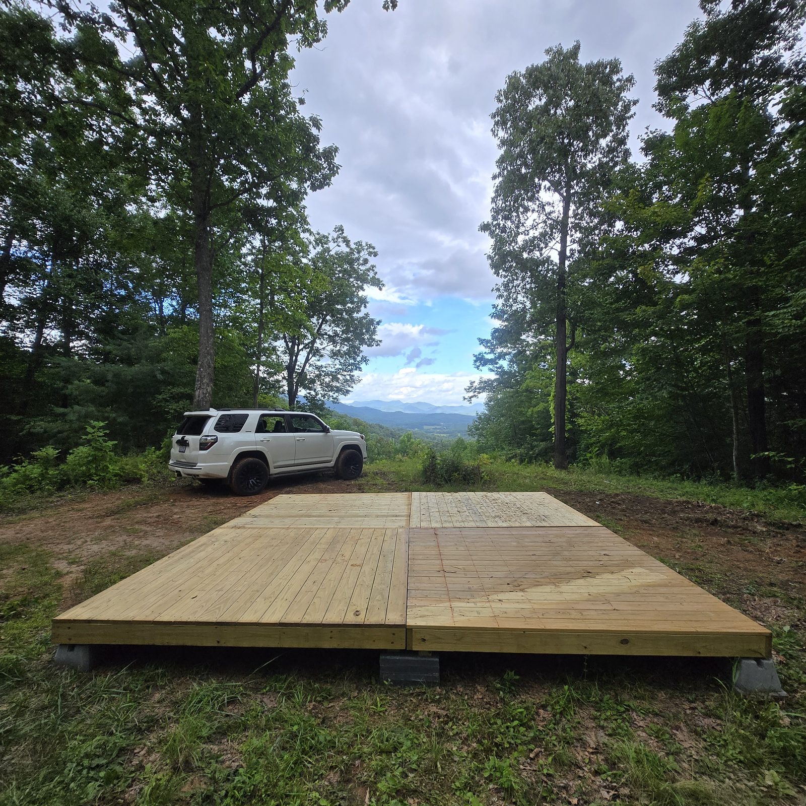 Campsite Big Bend 14 at Cardinal Mountain Campground: a tent deck with a vehicle alongside and mountain ridges beyond