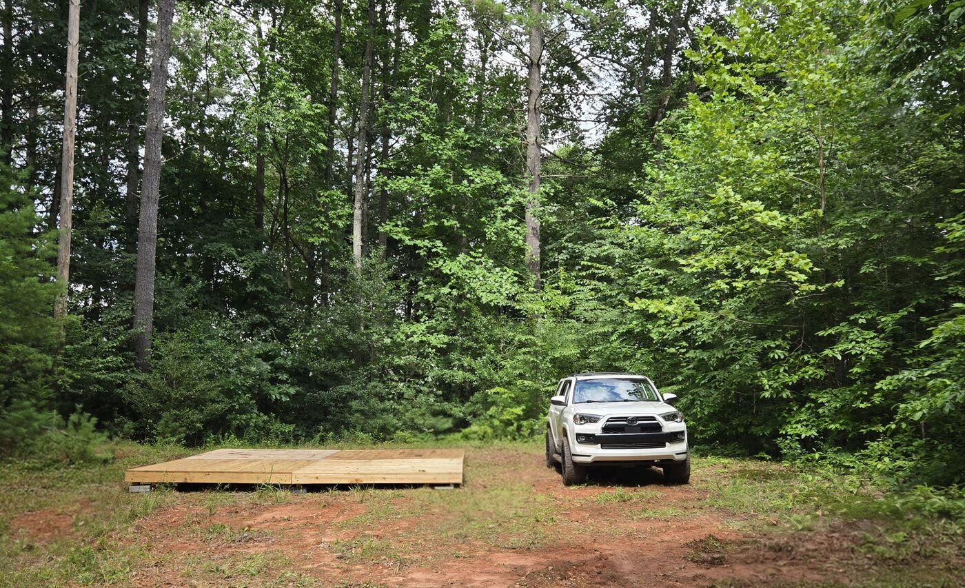A tent deck and parked vehicle at Blue Ridge 1, Cardinal Mountain Campground, with open ground between them