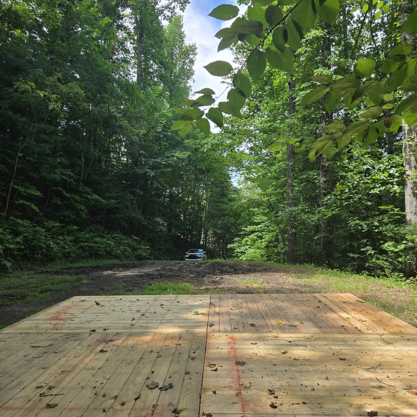 Looking down the long driveway from the deck at Nantahala 10, Cardinal Mountain Campground, with a vehicle parked at the far end