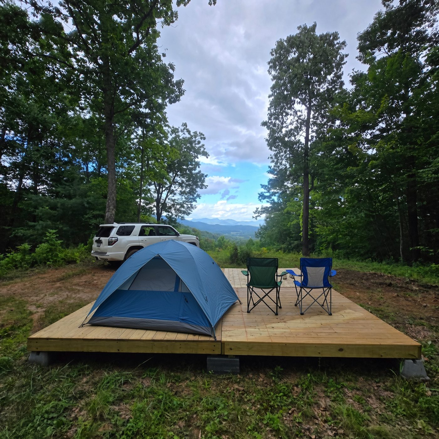 A tent and camp chairs on the deck at Big Bend 14, Cardinal Mountain Campground near Franklin NC, with a vehicle parked alongside and the valley opening out behind